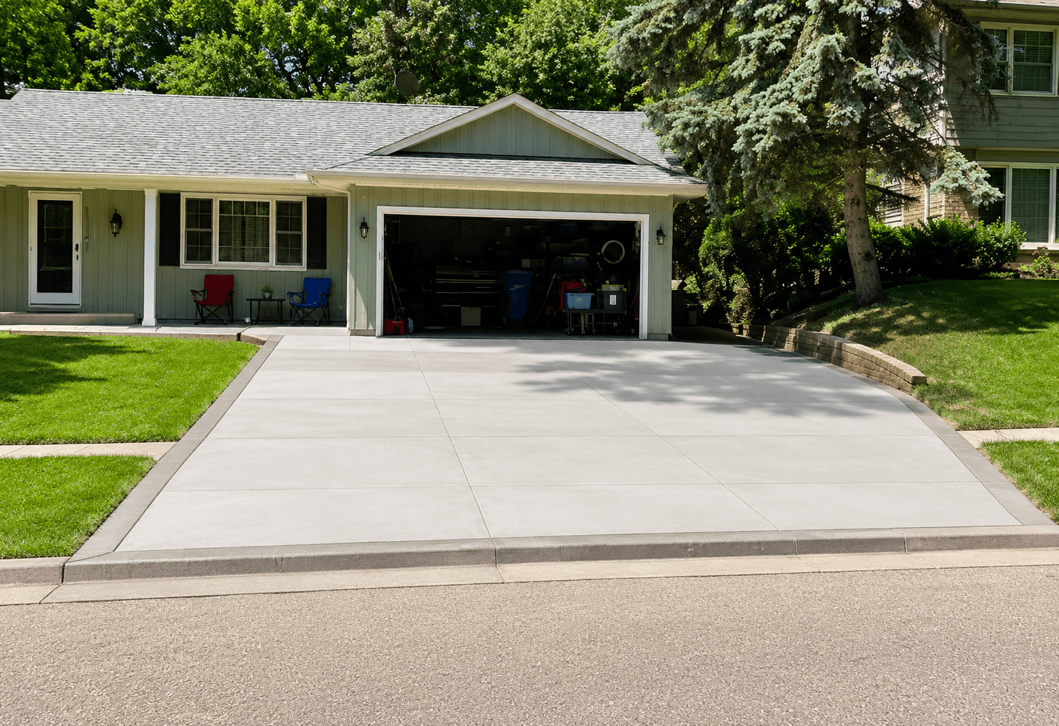 Two-car concrete driveway with river rock border edging by All-Pro Decks and Patios